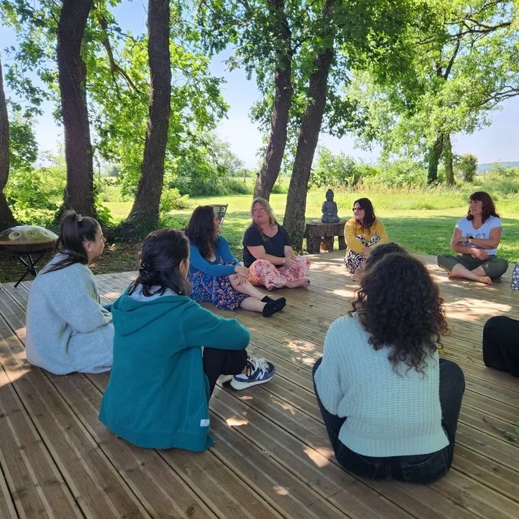 Cercle Photos de plusieurs personnes assises en tailleur devant la yourte. Plusieurs arbres en fond